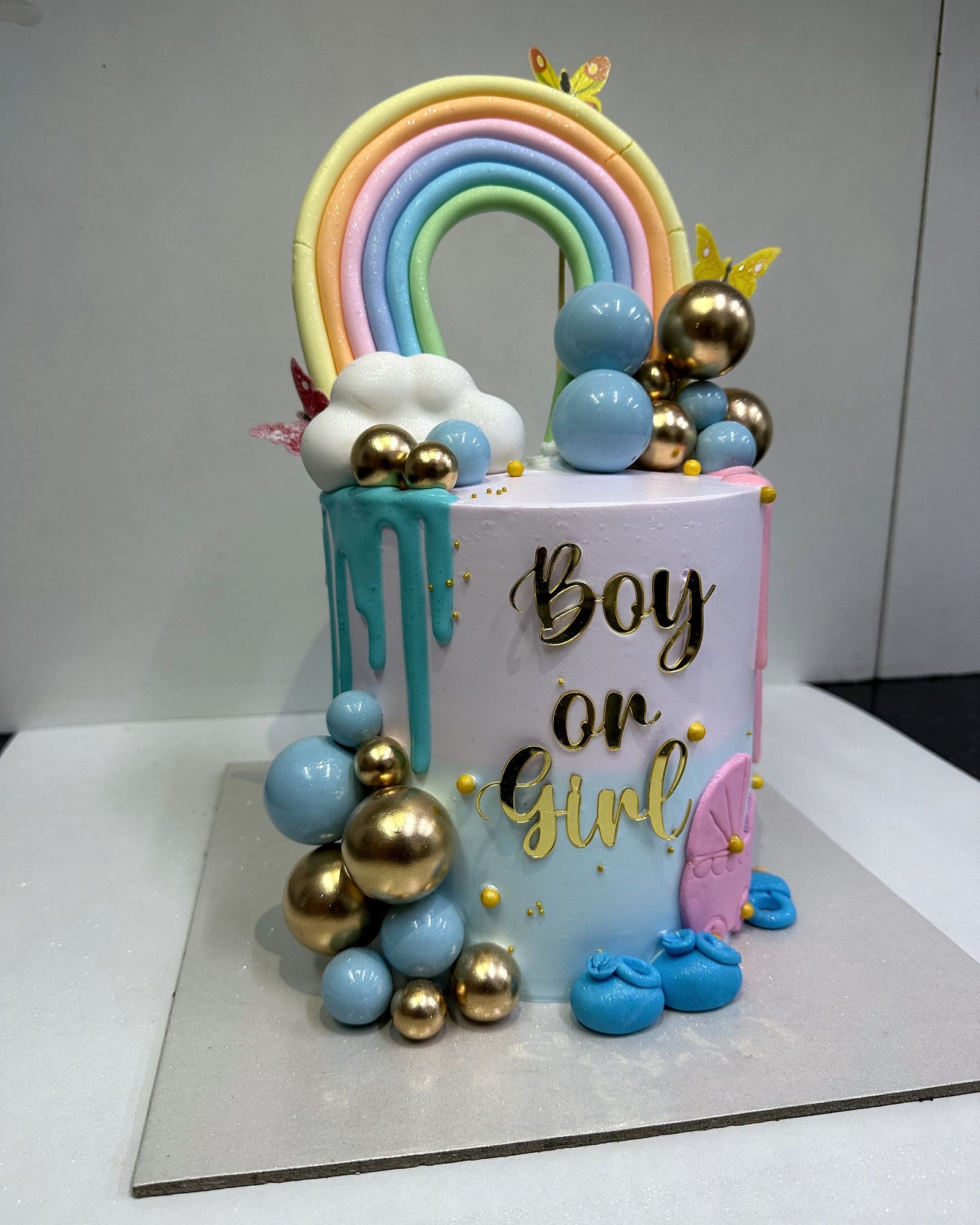 A “Boy or Girl” baby-shower height cake with gold and blue spheres