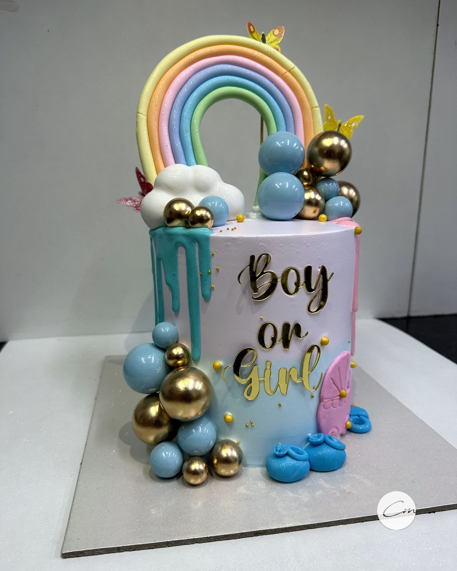A “Boy or Girl” baby-shower height cake with gold and blue spheres