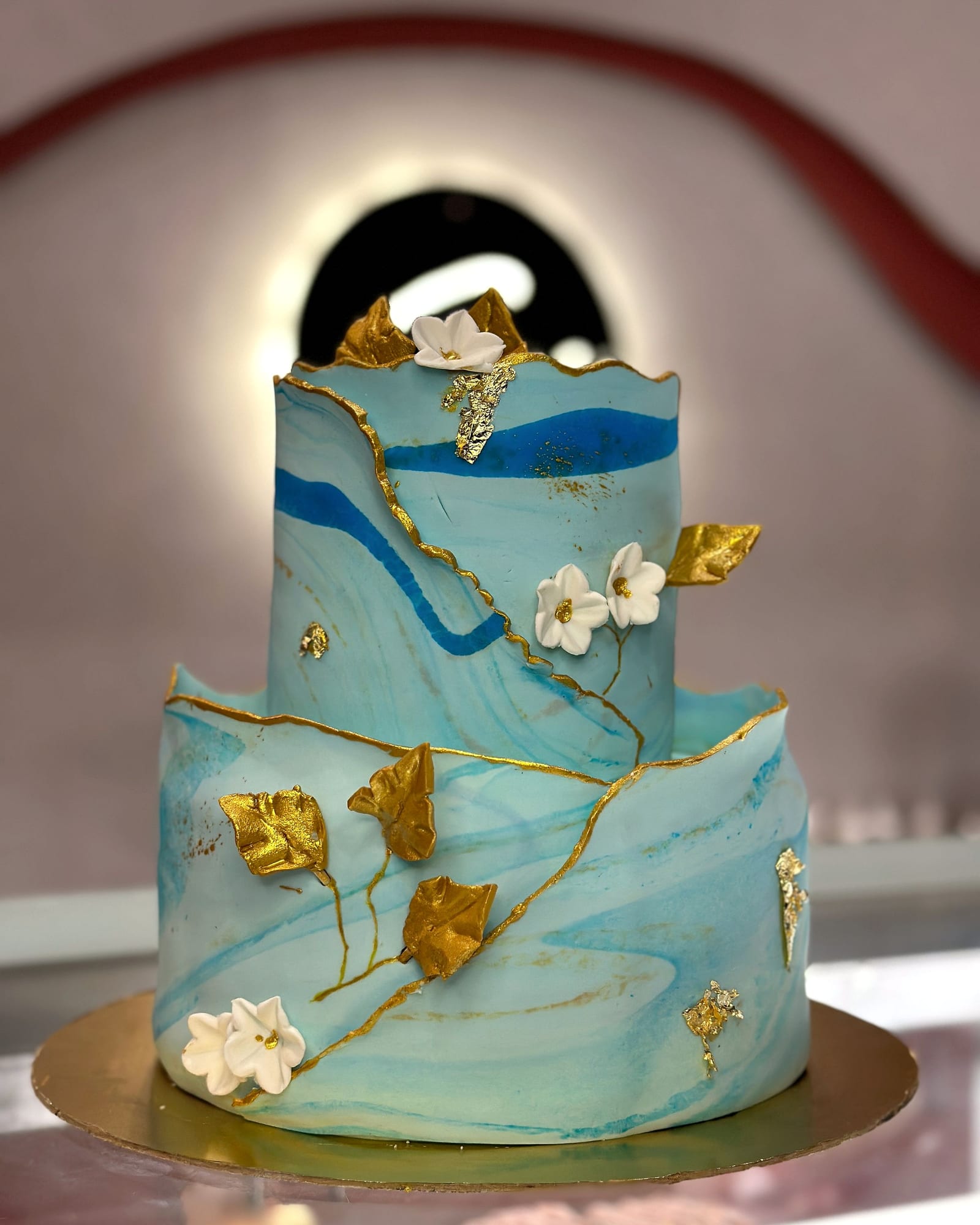 Two-tier blue marble fondant cake with gold leaf detailing