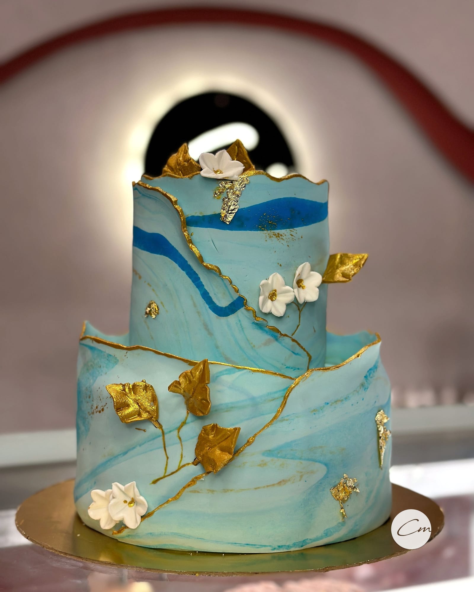 Two-tier blue marble fondant cake with gold leaf detailing
