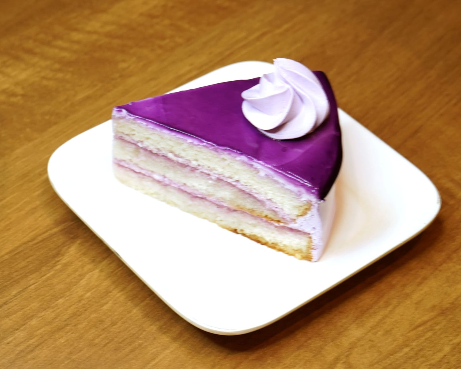A slice of blueberry cake under a violet mirror glaze