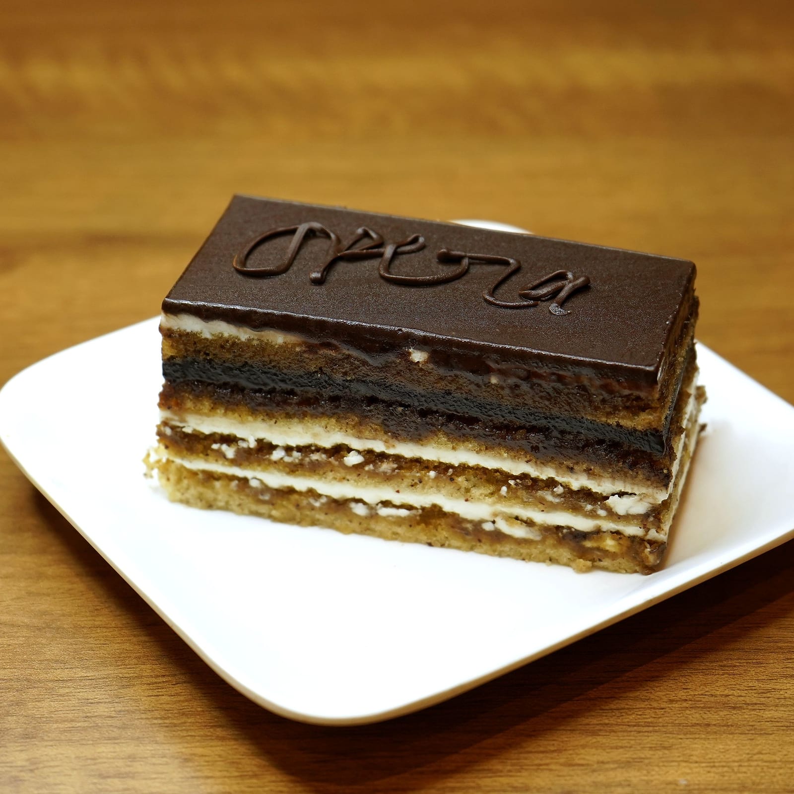 A slice of opera gateau with its chocolate name plaque