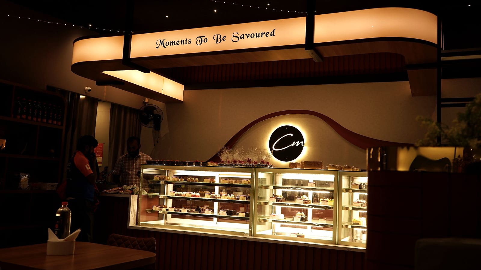 The Café Mellow counter in Tiruppur, dessert cases lit under the “Moments To Be Savoured” sign
