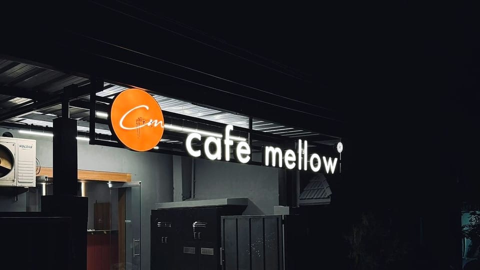 The lit Café Mellow shopfront sign on Muthusamy Street after dark
